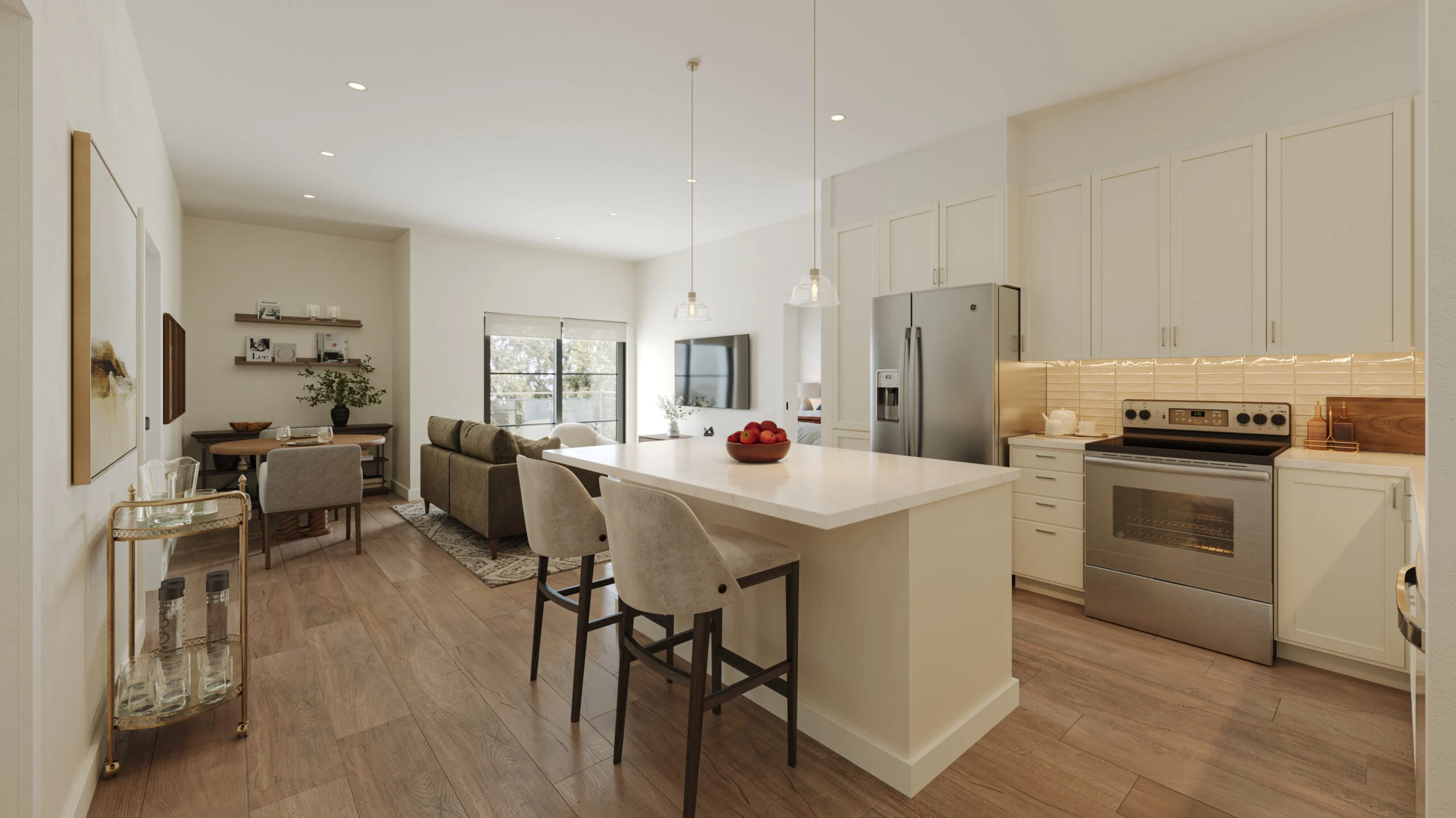 Open kitchen and living area with a large island, bar stools, stainless steel appliances, and comfortable seating in a senior living community setting.