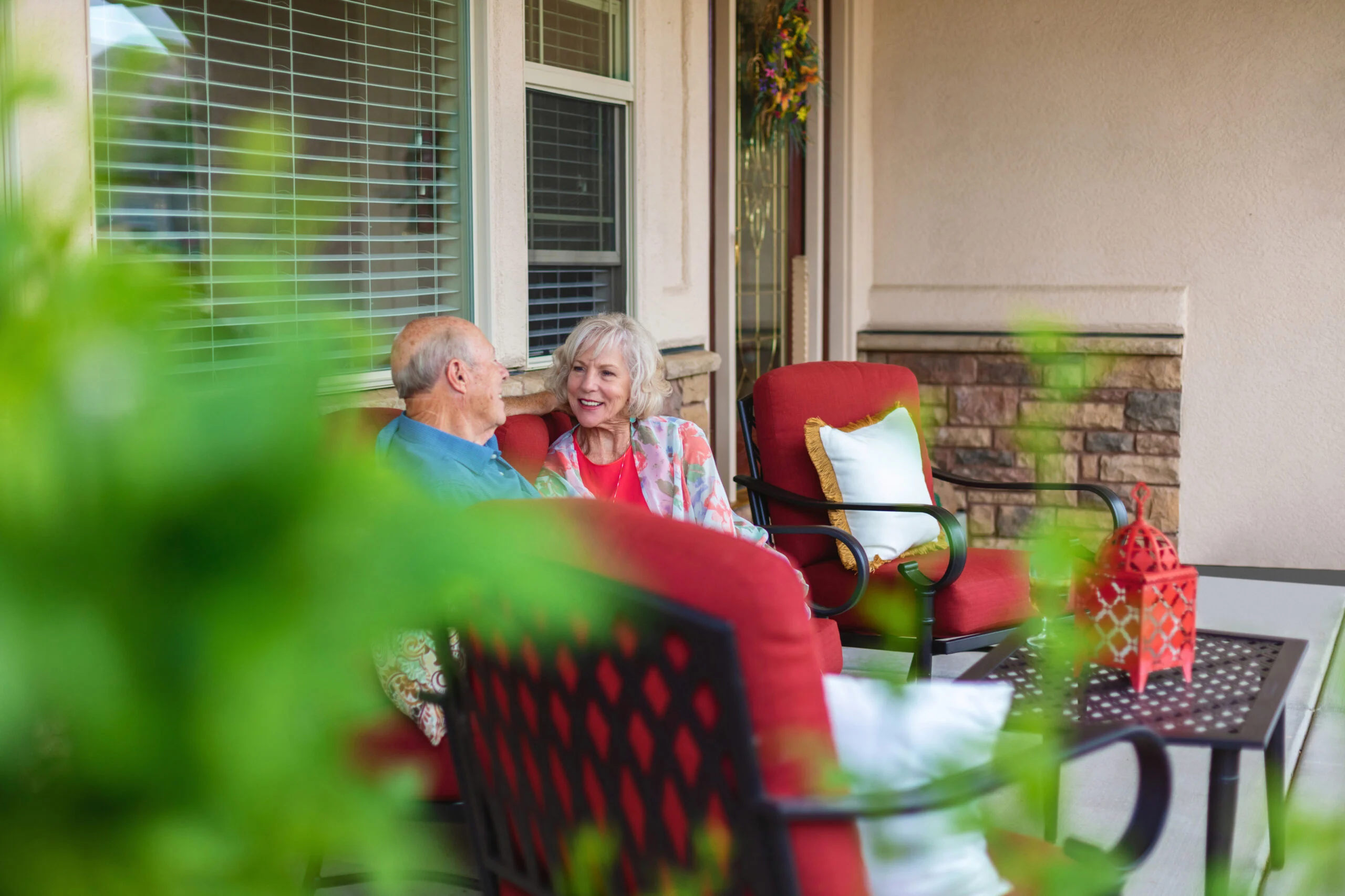 Two senior residents sitting and conversing on a furnished porch at The Providence Senior Living community.